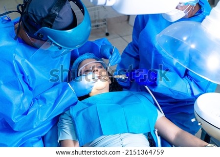 Dentists doing a endodontics to a female patient with brackets. Royalty-Free Stock Photo #2151364759