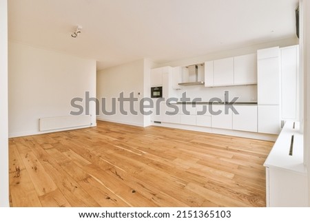 A spacious empty room with a corner kitchen on parquet floors in a minimalist style in a modern house