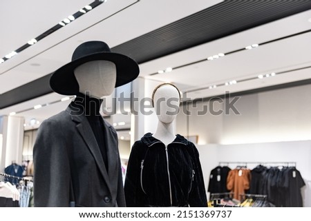Fashion mannequins at storefront window in shopping mall. Midseason sale at style clothes retailer. Discount designer apparel displayed in shop or boutique.