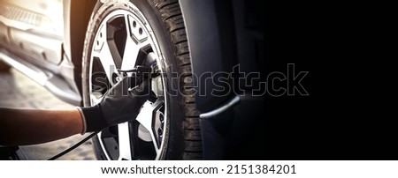 Auto mechanic checking air pressure and inflating car tires. Concept of car care service and maintenance or fix the car leaky or flat tire. Royalty-Free Stock Photo #2151384201