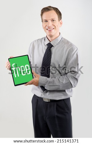 Smiling businessman showing a tablet isolated on light background