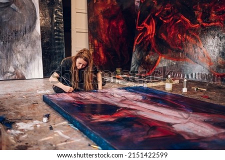 Portrait of a beautiful and authentic young female artist or painter creating art piece in a studio. Art, creativity, hobby, job and creative occupation concept. Professional painter at work.
