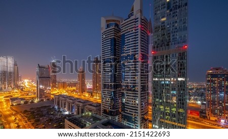 Aerial view of Dubai International Financial District with many skyscrapers night to day transition timelapse. Traffic on a road junction on Sheikh Zayed road before sunrise. Dubai, UAE. Royalty-Free Stock Photo #2151422693