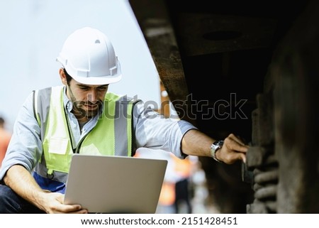 Mechanical engineer or professional maintenance technician wearing safety clothing is using a wrench to repair and inspect the undercarriage of the train, have double exposure images, and bokeh. Royalty-Free Stock Photo #2151428451