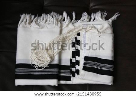 Folded tallit on a leather background. A folded Jewish prayer garment. Royalty-Free Stock Photo #2151430955