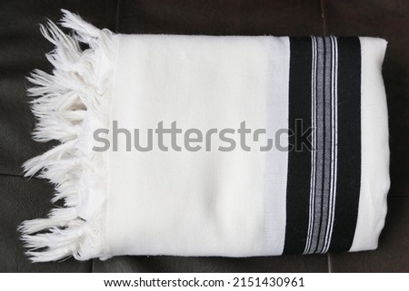 Folded tallit on a leather background. A folded Jewish prayer garment. Royalty-Free Stock Photo #2151430961