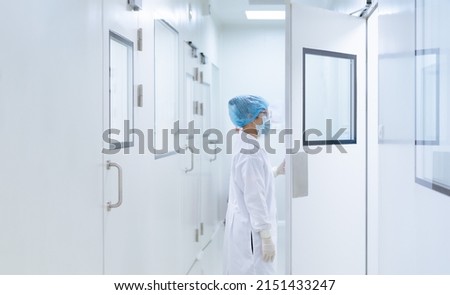 Unidentified microbiologist is open the cleanroom door to enter the room in clean area of microbial laboratory in pharmaceutical factory, concept of science, healthcare and safety operation. Royalty-Free Stock Photo #2151433247