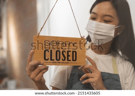 Asian young owner retail,coffee shop woman turning sign board to closed with wearing face mask,protection to pandemic of coronavirus.Close store,restaurant or pub due to lockdown, quarantine of covid.