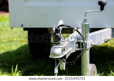 Small luggage trailer on green grass, focus on the electrical connectiom. Royalty-Free Stock Photo #2151443723