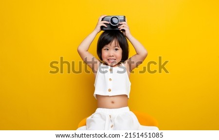 Asian female photographer taking a picture on a yellow background Has a cute smile like a childhood