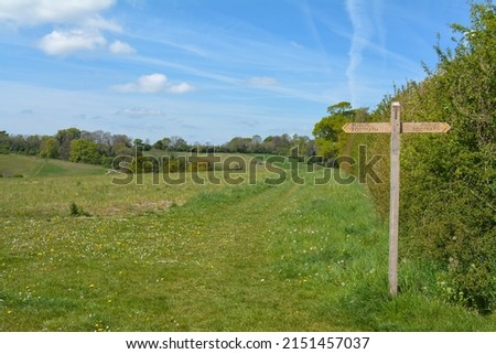 Public footpath wooden sign in the middle of a beautiful Hampshire countryside scene.