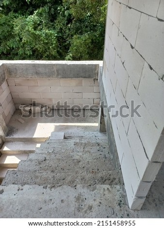 photo of the room is under construction with a rough finish, plastered walls, concrete floor,Modern house with landscaping on front,Entrance porch with concrete floor and square columns. Exterior hous
