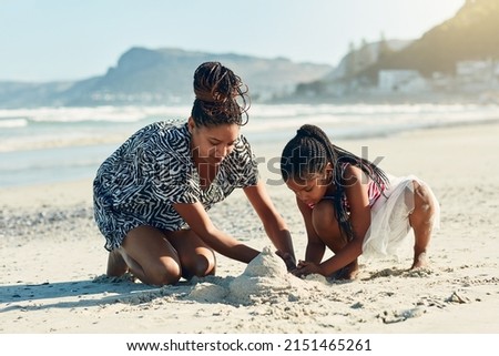 Its their favourite beach activity. Shot of a mother and her little daughter building a sandcastle together at the beach. Royalty-Free Stock Photo #2151465261