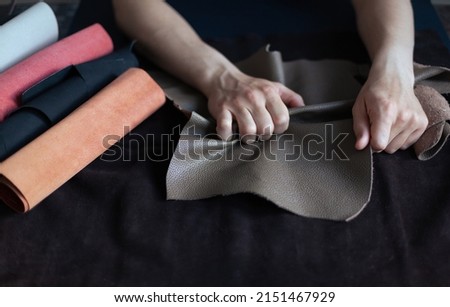 A professional craftsman, sitting at his desk and choosing cowhide in a roll for making leather products