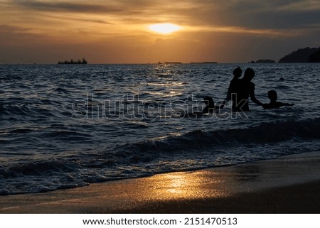 The silhouettes of people swimming in the ocean at scenic sunset