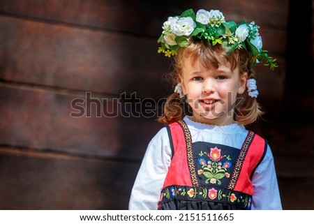 Adorable little girl in Swedish traditional clothes wearing flower wreath during Midsommar festival celebration Royalty-Free Stock Photo #2151511665