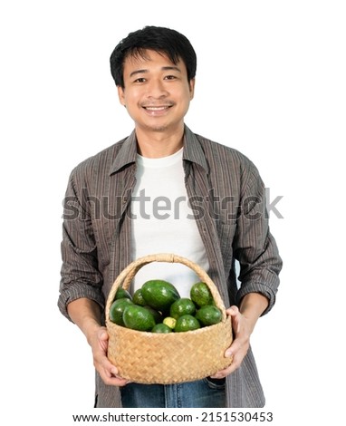 Asian male farmer holding a basket of avocados isolated from the white background