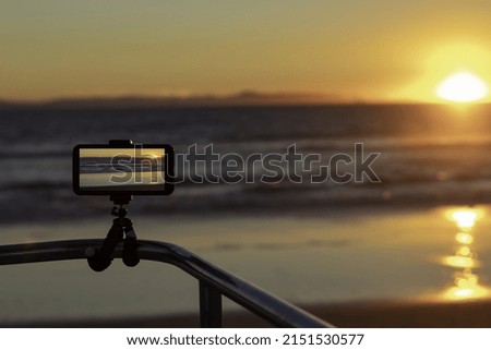 A smartphone on a tripod for taking pictures in Huntington Beach, California at sunset