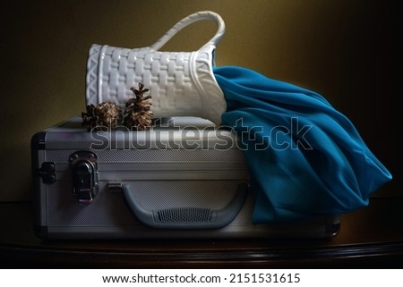 Jakarta, May 1, 2022. Tea pot, cup and blue cloth on aluminum suitcase. Fine art photography. Light painting photography. Still-life photography.                               