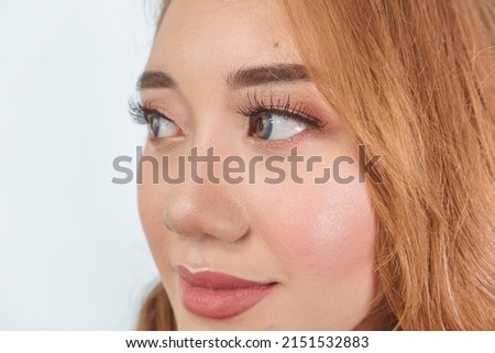 A beautiful Filipina model showing the results of a professional makeup session. Wearing contact lens and sporting brilliant copper dyed hair. Royalty-Free Stock Photo #2151532883