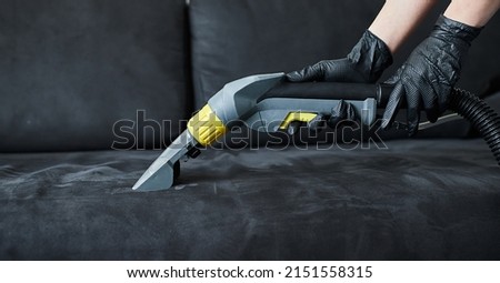 Cleaning service company employee removing dirt from furniture in flat with professional equipment. Female housekeeper arm cleaning sofa with washing vacuum cleaner close up Royalty-Free Stock Photo #2151558315