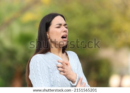Stressed woman having breath problems walking in a park Royalty-Free Stock Photo #2151565201