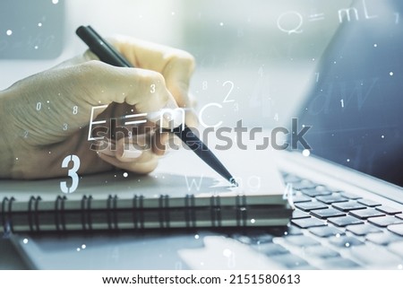 Double exposure of creative scientific formula concept with hand writing in notebook on background with laptop, research and development concept