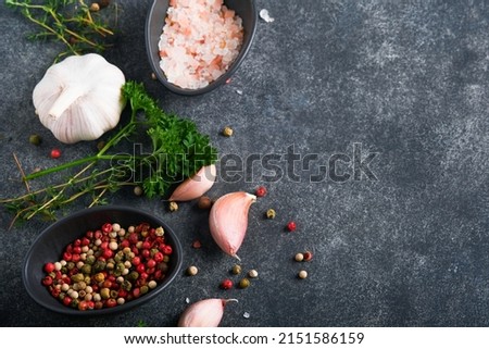 Black food cooking background. Stone texture with sea salt, pepper garlic and parsley. Abstract food background. Empty space for text. Can be used for food posters, design of menu. Top view.