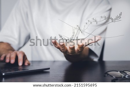 Man holding cryptocurrency chart on the palm, male person working on the laptop on stock market, crypto trading concept. Graphic chart in air.