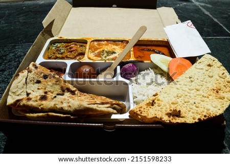 Tasty Indian lunch pack parcel of packed food consisting of variety of items like tandoori roti, rice, salad, pickle