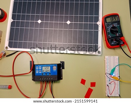 Arduino project powered through energy from small solar panels. Voltmeter uses for mesuring voltage from little photovoltaic panel. Charge  regulator, battery, tester, Led, insulating tape. Royalty-Free Stock Photo #2151599141