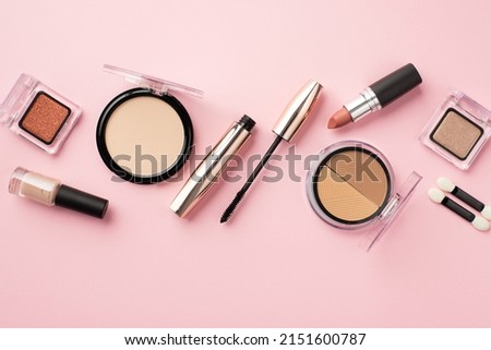 Make up concept. Top view photo of lipstick compact powder blush eyeshadow brushes nail polish and mascara on pastel pink background