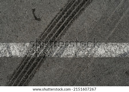 Asphalt texture with white line and tire marks. Smooth asphalt road. Tarmac dark grey grainy road background.Top view Royalty-Free Stock Photo #2151607267