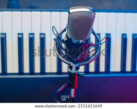 Modern microphone and midi keyboard, synthesizer. Minimalism. There are no people in the photo. Professional recording studio, home music studio. Music, vocals, radio recording.