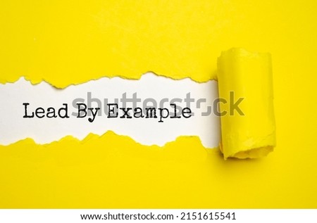The text Lead by example appearing behind torn brown paper Royalty-Free Stock Photo #2151615541