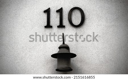 A closeup of the number 101 on the light gray wall with an old lamp 