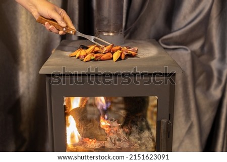 Female hand stirring roasted pinions on the wood burning stove with a fork. Pine nuts from Araucaria angustifolia, South American pine tree