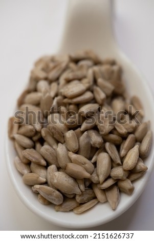 sunflower seeds in a white spoon blurred with white background