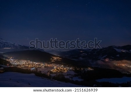 A photo of houses and mountains in snow in Falera, Surselva, Switzerland by night