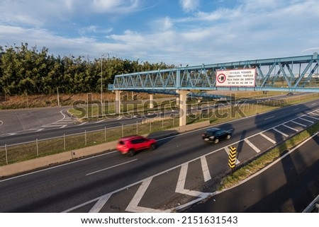 Traffic on the highway and pedestrian bridge. Sign indicating for trucks to use the right lane. D. Pedro I Highway, Atibaia, Brazil. Royalty-Free Stock Photo #2151631543
