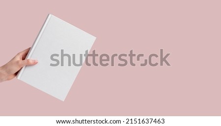 Banner with hand holding book mockup on pink, pastel background. Education, reading, research conducting, getting knowledge concept. Copy space. High quality photo