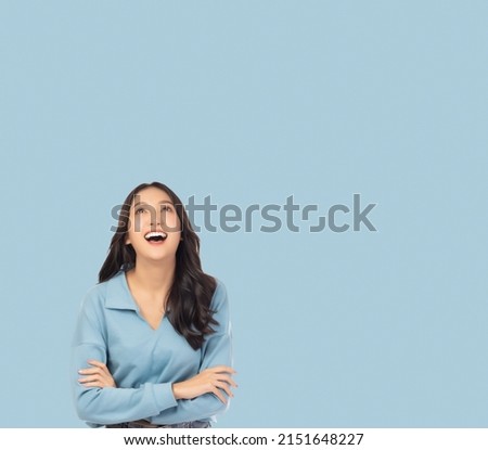 Portrait smiling young asian woman with crossed arms Happy asia girl posing with crossed arms and looking at above stand over light blue background and copy space Confident female get happy and  relax Royalty-Free Stock Photo #2151648227