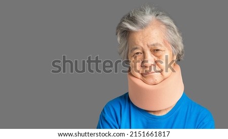 Portrait of a senior woman wearing a soft neck collar because suffering neck pain and neck tilt while standing on a gray background. Medical and healthcare concept