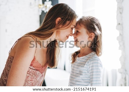 Young mother woman with long hair with little tween girl daughter in pajamas having fun in the morning at home