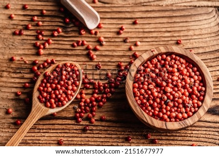 Red pepper corns in wood bowl on wooden table i. Pink peppercorns seeds. Brazil Pepper Royalty-Free Stock Photo #2151677977