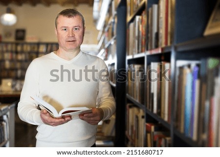 Intelligent male reading interesting books in bookstore