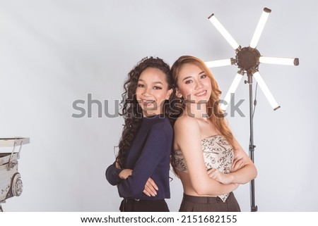 Two attractive asian models posing back to back. Two close friends having fun. During a photoshoot at a modelling agency.