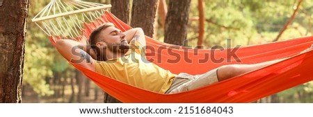 Handsome young man relaxing in hammock outdoors