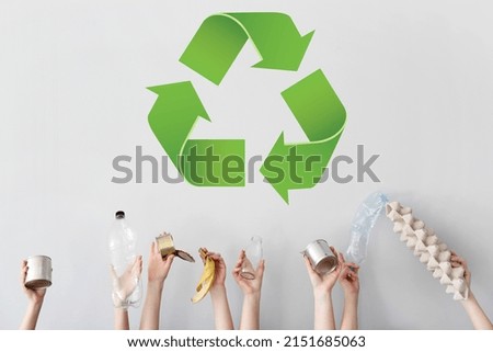 Hands with different types of garbage and recycling sign on light background