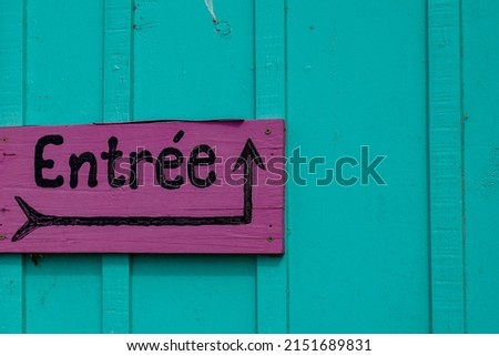 pink sign indicating entree in french text means entry with black arrow